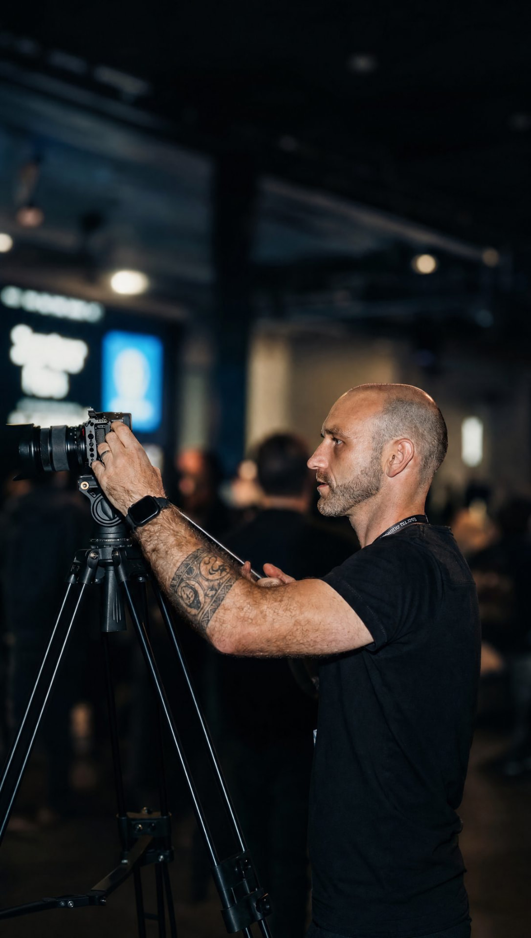 Adam filming on a tripod-mounted cinema camera at a live event